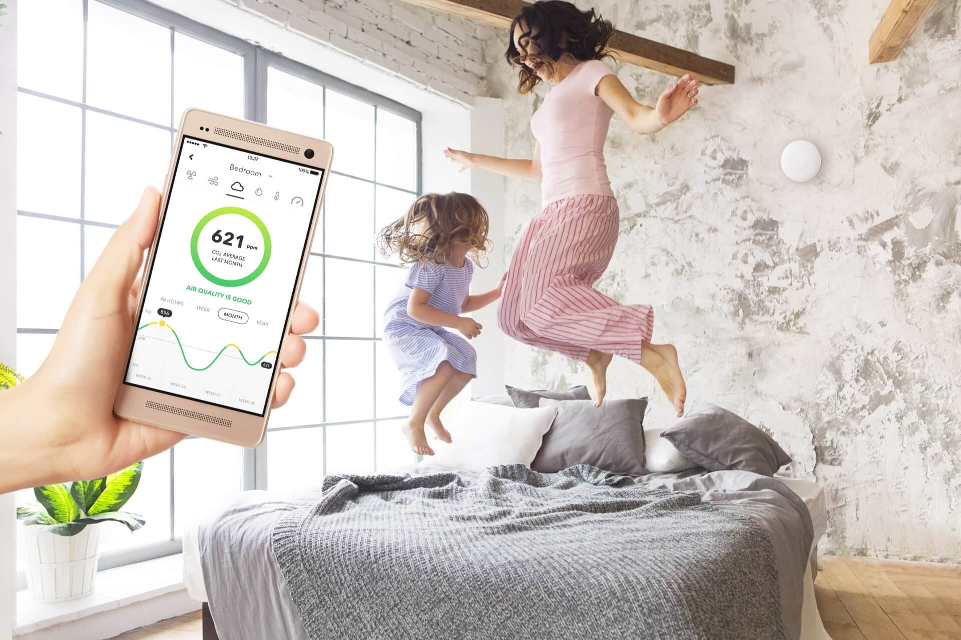 Air quality monitor and happy family breathing fresh air